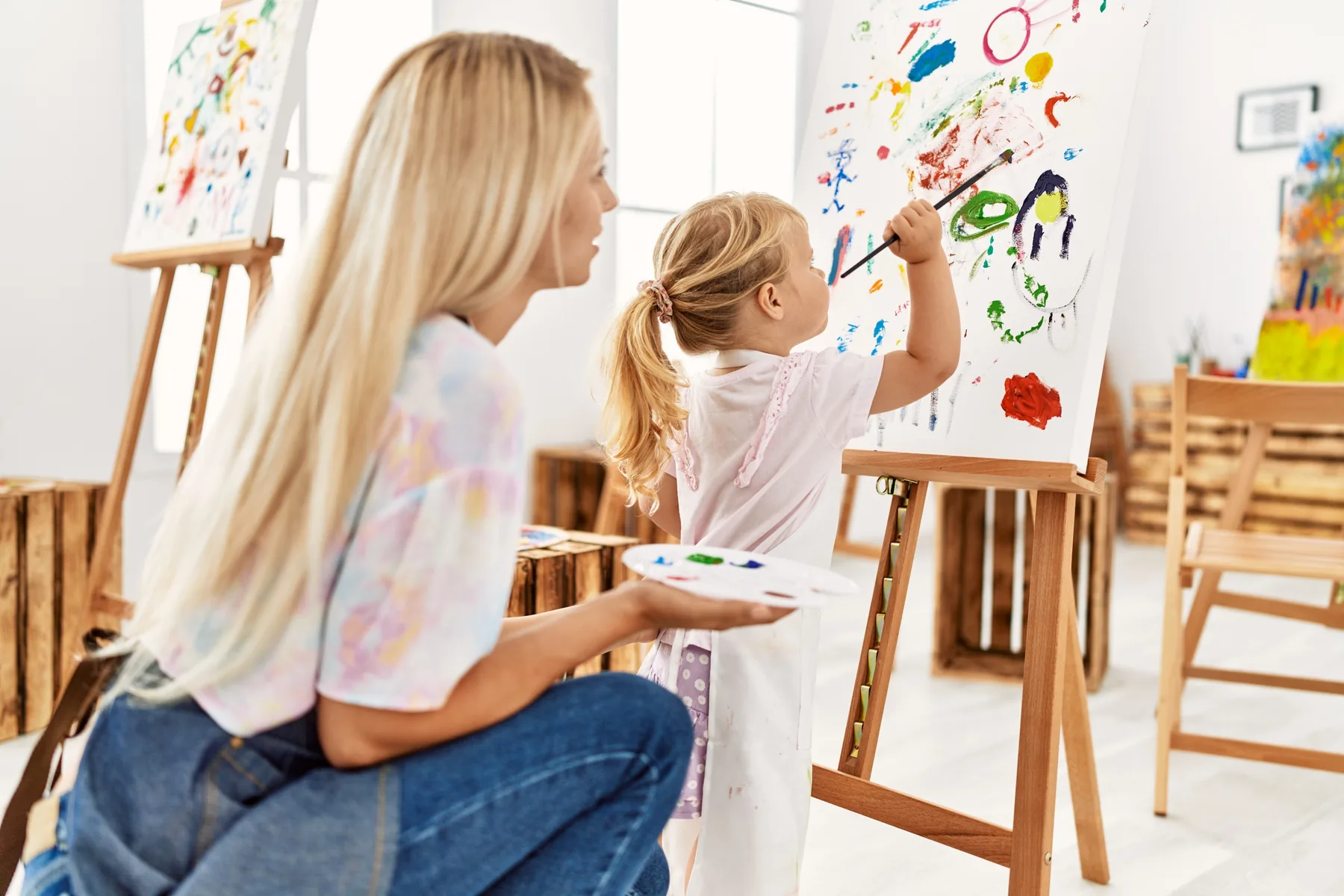 Taller de arte: niña pintando un lienzo junto a su madre